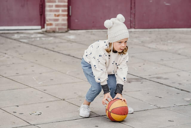 ילדה משחקת עם כדור ברחוב